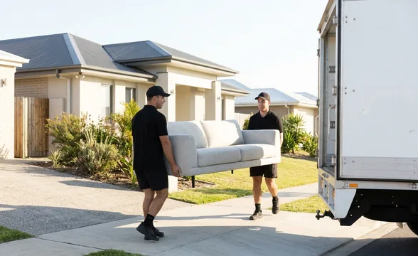 Two Legendz removalists carrying a sofa to the truck during a home move